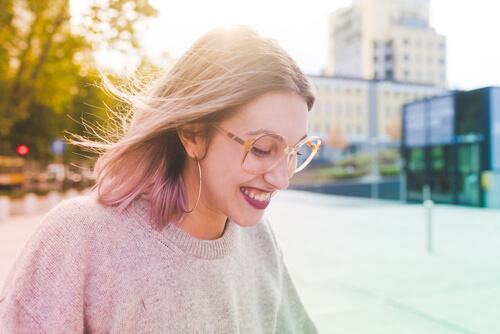 woman in tan sweater and sunglasses walking down the street